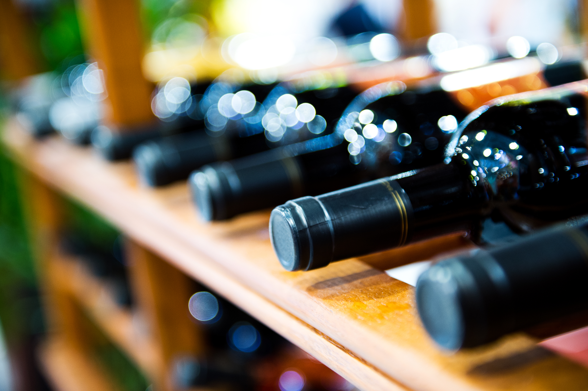 “Close-up of wine bottles on a wooden rack, representing the wine and spirits industry”