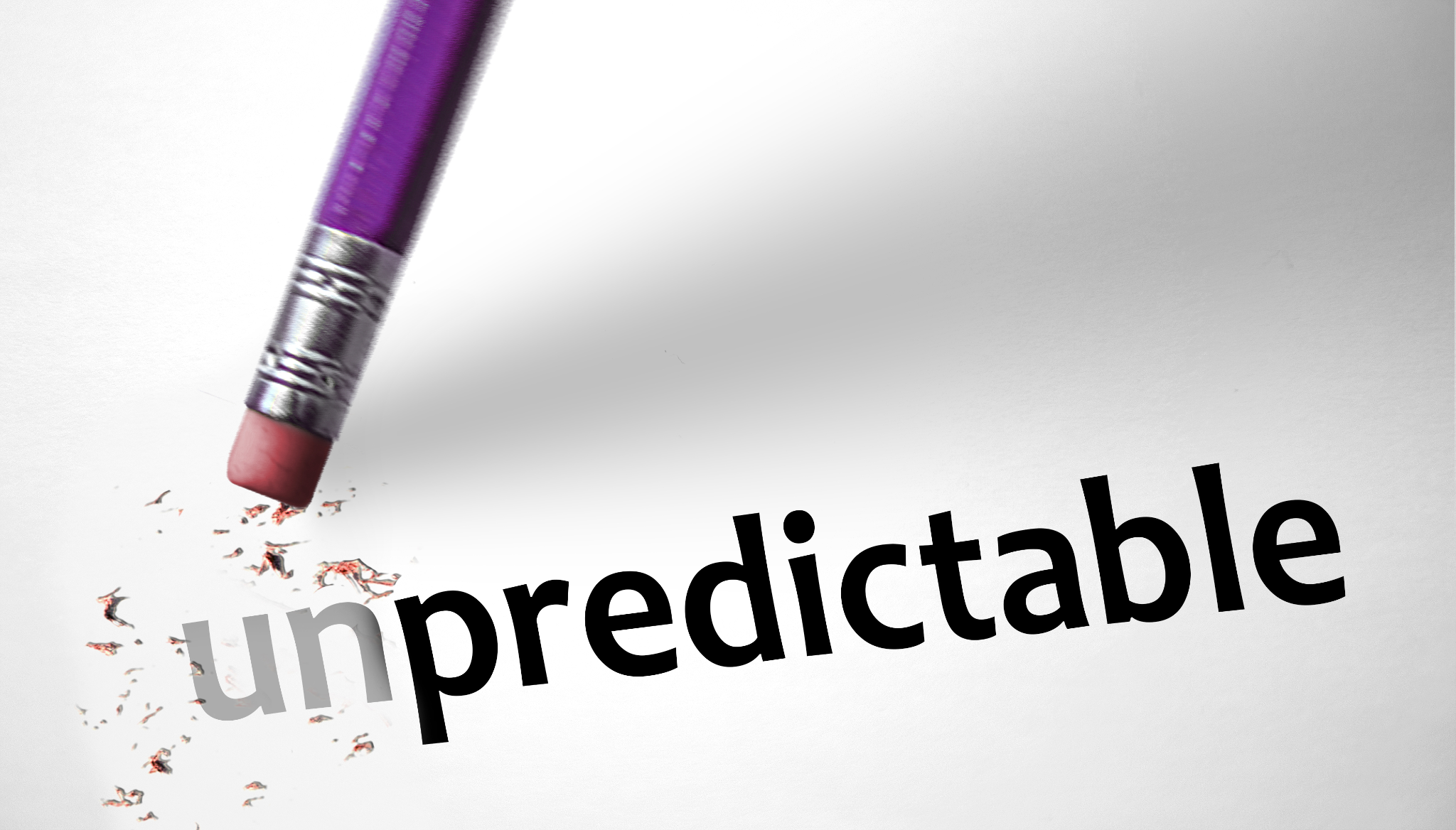 "A pencil eraser removing the "un" from the word "unpredictable," leaving the word "predictable," with eraser shavings around".