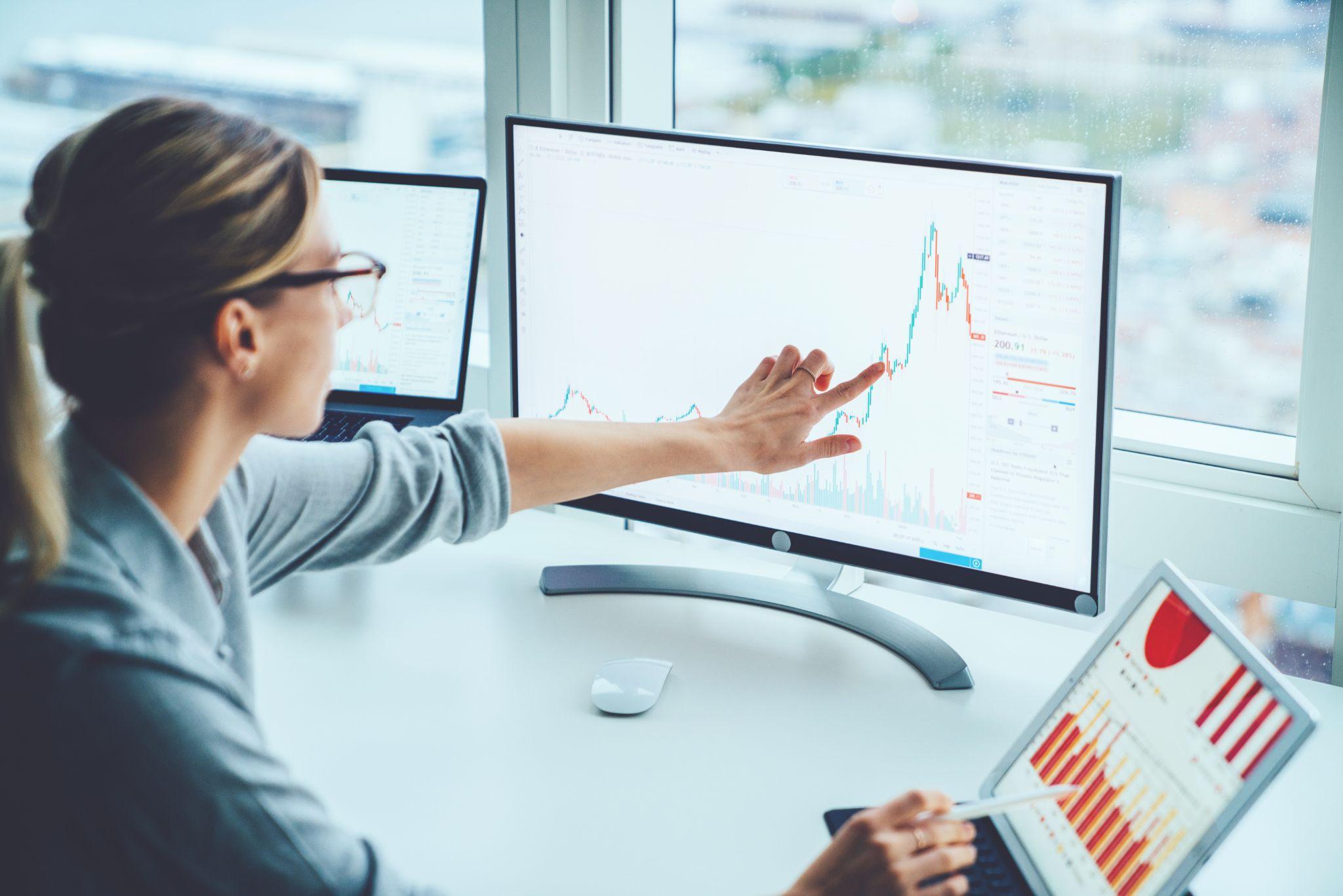 Businesswoman studies financial market risks and profits, calculating money with statistics graphs on computer screen